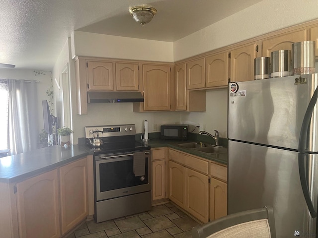 kitchen with dark countertops, appliances with stainless steel finishes, a sink, a peninsula, and under cabinet range hood