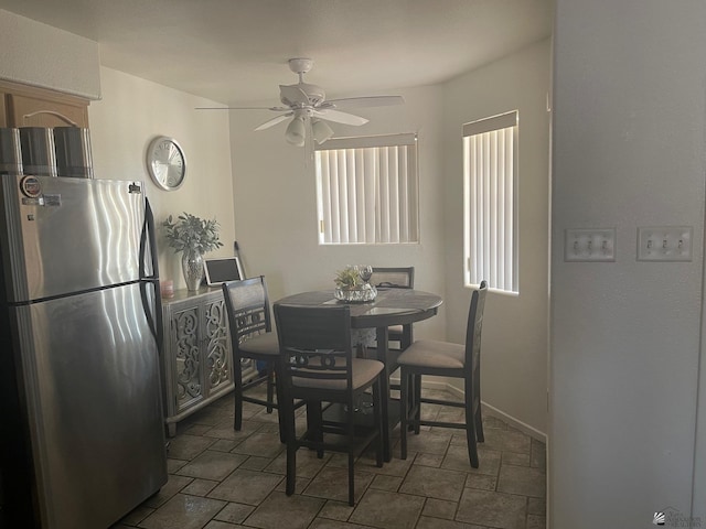 dining area featuring stone finish floor, ceiling fan, and baseboards