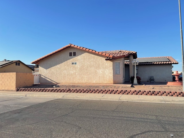 mediterranean / spanish-style house with fence, stucco siding, and a tile roof
