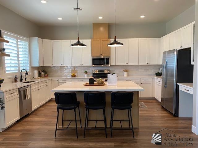 4595 S Villa Serena Drive Model Home Not For Sale, Yuma, AZ 85365 - kitchen with a kitchen island, a kitchen bar, tasteful backsplash, a sink, and stainless steel appliances