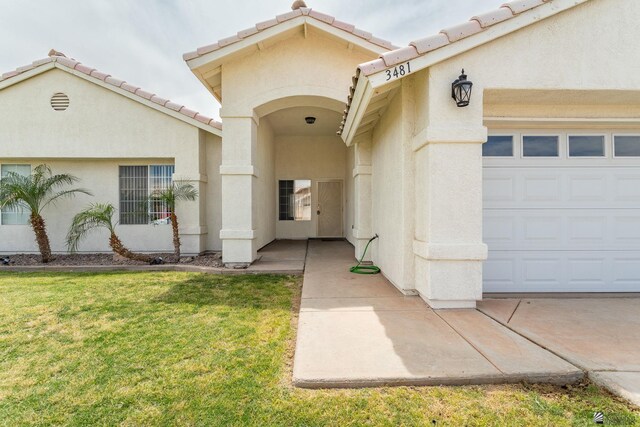 3481 W 27th Ln, Yuma, AZ 85364 - view of exterior entry with a yard, stucco siding, a garage, and a tile roof