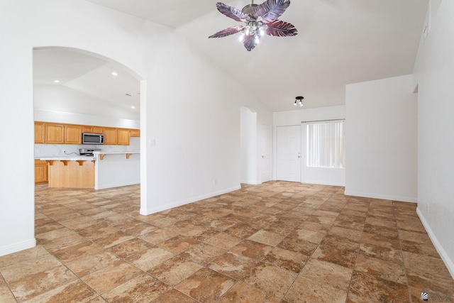3481 W 27th Ln, Yuma, AZ 85364 - unfurnished living room with lofted ceiling, light stone finish flooring, a ceiling fan, baseboards, and arched walkways