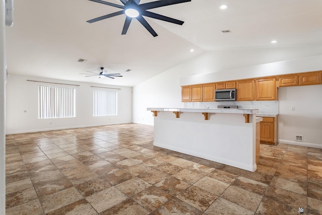 3481 W 27th Ln, Yuma, AZ 85364 - kitchen featuring stainless steel microwave, a ceiling fan, light countertops, baseboards, and a breakfast bar