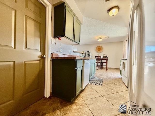 kitchen featuring white appliances, light tile patterned flooring, and a textured ceiling