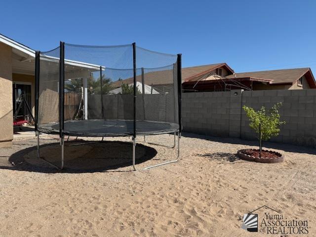 view of yard featuring a trampoline and a fenced backyard