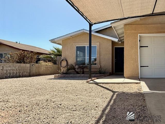 view of exterior entry featuring stucco siding and fence