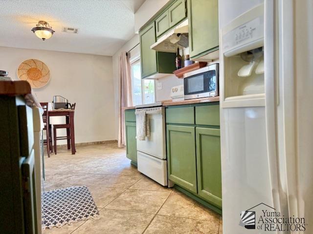 kitchen with visible vents, white appliances, a textured ceiling, and green cabinets