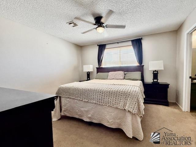 bedroom featuring baseboards, visible vents, ceiling fan, a textured ceiling, and light carpet