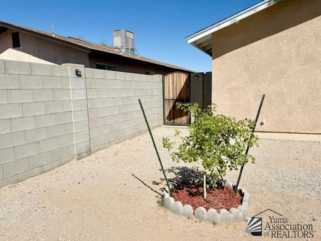 view of property exterior featuring a gate, fence, and stucco siding