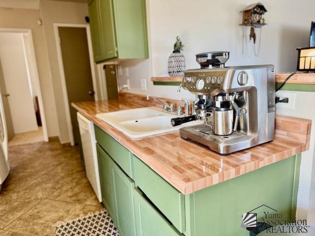 kitchen featuring butcher block countertops, a sink, dishwasher, and green cabinetry