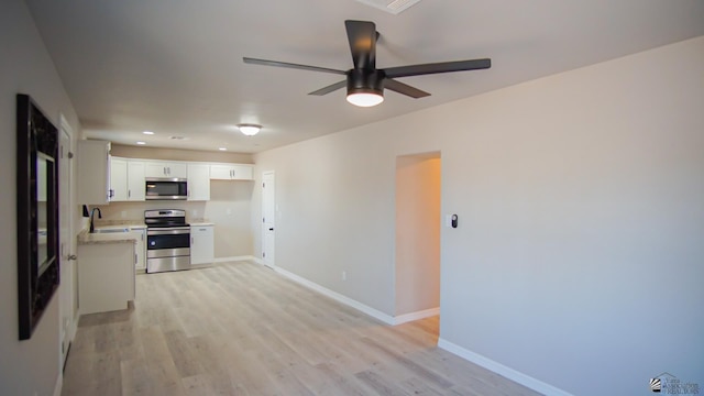 kitchen featuring sink, light hardwood / wood-style flooring, ceiling fan, white cabinetry, and stainless steel appliances