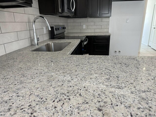 10744 E 45th Pl, Yuma, AZ 85367 - kitchen with stainless steel appliances, light stone counters, a sink, dark cabinets, and tasteful backsplash
