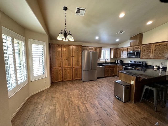 kitchen with sink, an inviting chandelier, pendant lighting, vaulted ceiling, and appliances with stainless steel finishes