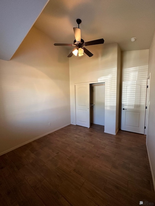 unfurnished bedroom with ceiling fan, lofted ceiling, dark wood-type flooring, and a closet