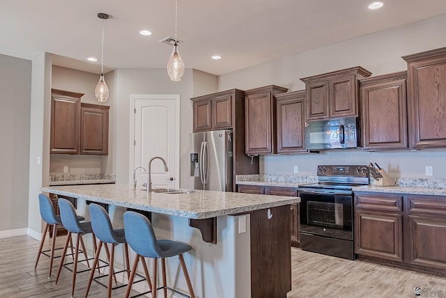 14769 E 47th Ln, Yuma, AZ 85367 - kitchen with black appliances, a sink, light wood-style floors, a center island with sink, and a breakfast bar area