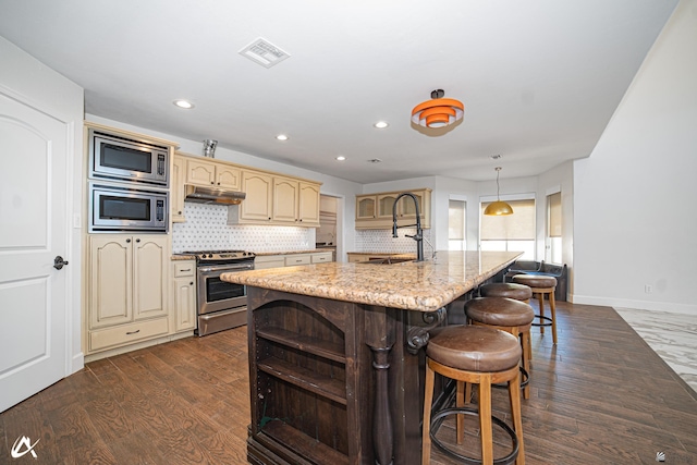 2864 W 12th Ln, Yuma, AZ 85364 - kitchen featuring appliances with stainless steel finishes, under cabinet range hood, dark wood-type flooring, cream cabinets, and recessed lighting