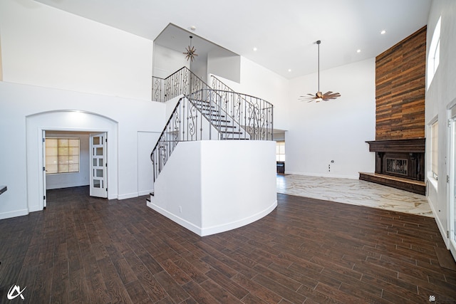 2864 W 12th Ln, Yuma, AZ 85364 - unfurnished living room featuring stairway, a high ceiling, wood finished floors, a large fireplace, and arched walkways
