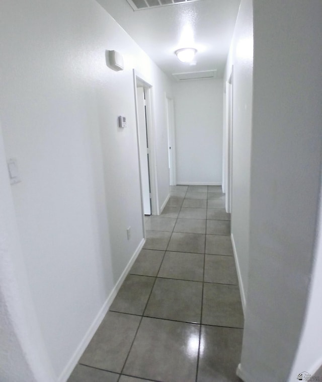 hallway featuring tile patterned floors and baseboards