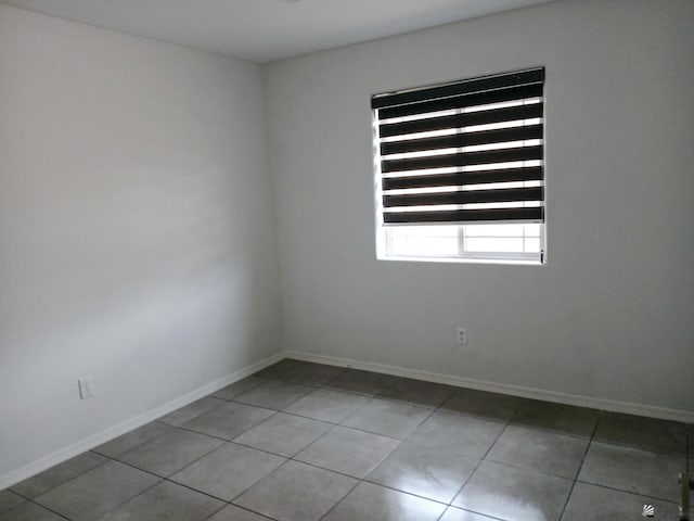 empty room featuring tile patterned flooring and baseboards