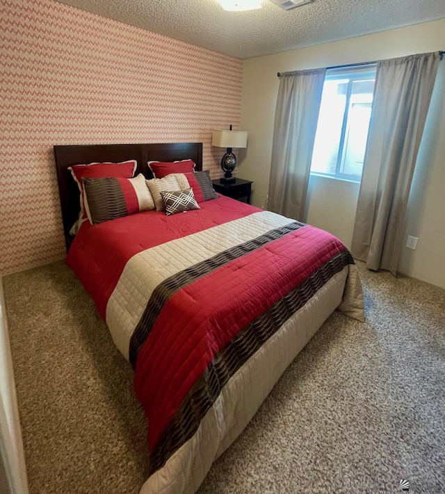 carpeted bedroom featuring visible vents, a textured ceiling, and wallpapered walls