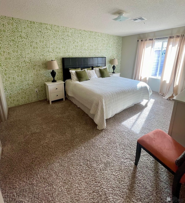 carpeted bedroom with wallpapered walls, a textured ceiling, and visible vents