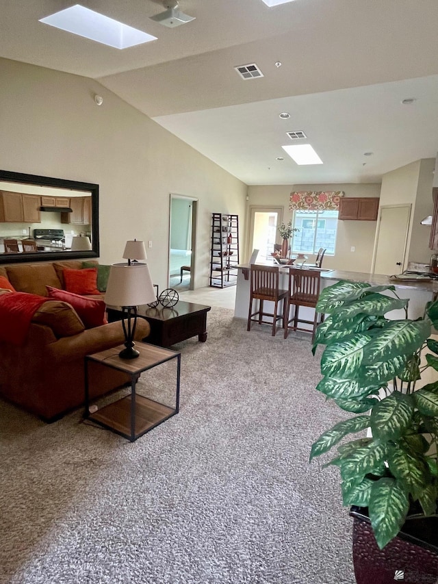 living area with vaulted ceiling with skylight, light carpet, and visible vents