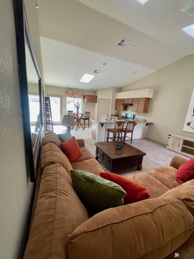 living room with visible vents, light carpet, and vaulted ceiling with skylight