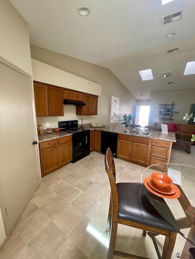 kitchen with a sink, black appliances, a peninsula, visible vents, and lofted ceiling with skylight