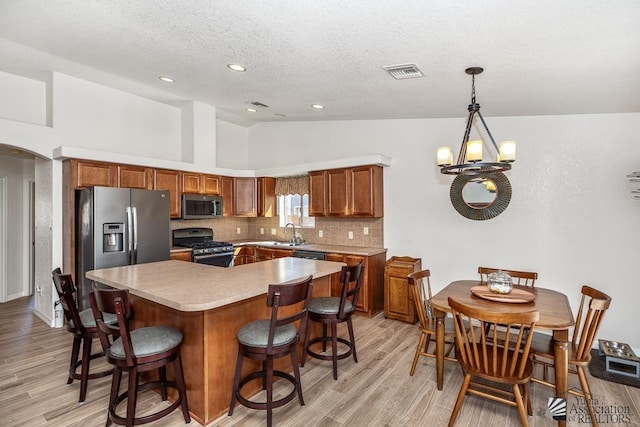 11861 E Eclipse Ct, Yuma, AZ 85367 - kitchen featuring a textured ceiling, light wood finished floors, appliances with stainless steel finishes, and lofted ceiling