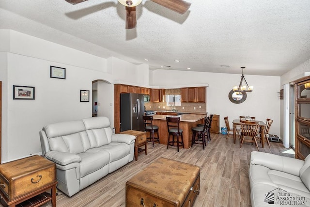11861 E Eclipse Ct, Yuma, AZ 85367 - living room with arched walkways, a textured ceiling, ceiling fan with notable chandelier, lofted ceiling, and light wood-type flooring