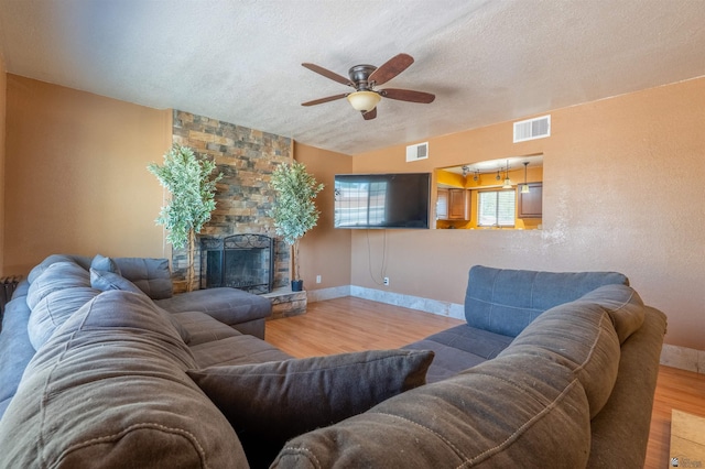 2931 W 20th St, Yuma, AZ 85364 - living room featuring wood finished floors, a textured ceiling, ceiling fan, baseboards, and a stone fireplace