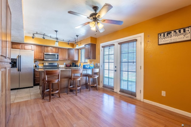 2931 W 20th St, Yuma, AZ 85364 - kitchen with stainless steel appliances, light wood finished floors, a peninsula, ceiling fan, and a breakfast bar area