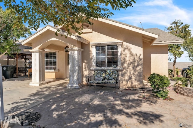 view of front of home with stucco siding and a patio area