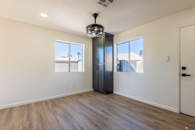 empty room with recessed lighting, baseboards, visible vents, and wood finished floors