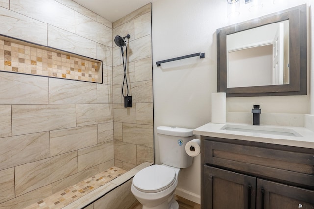 bathroom featuring vanity, baseboards, toilet, and tiled shower
