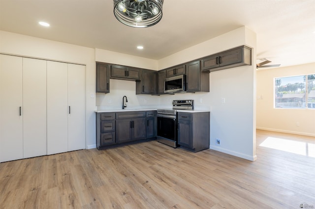 kitchen featuring dark brown cabinetry, baseboards, light countertops, light wood finished floors, and appliances with stainless steel finishes