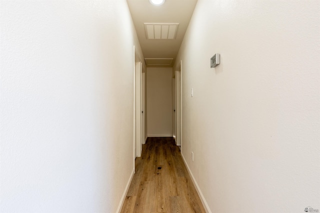 hall featuring baseboards, light wood finished floors, and visible vents