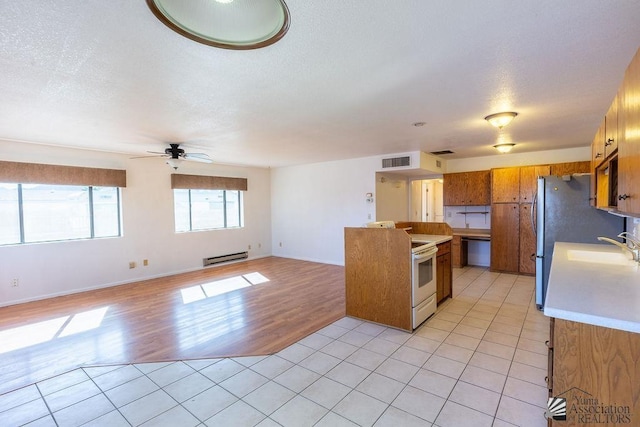 13125 E 51st Ln, Yuma, AZ 85367 - kitchen with visible vents, brown cabinetry, ceiling fan, light countertops, and a baseboard heating unit