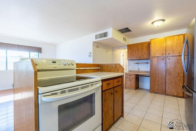 13125 E 51st Ln, Yuma, AZ 85367 - kitchen featuring white range with electric cooktop, freestanding refrigerator, brown cabinetry, and visible vents