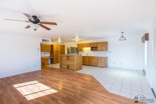 13125 E 51st Ln, Yuma, AZ 85367 - kitchen with visible vents, freestanding refrigerator, brown cabinetry, decorative backsplash, and ceiling fan