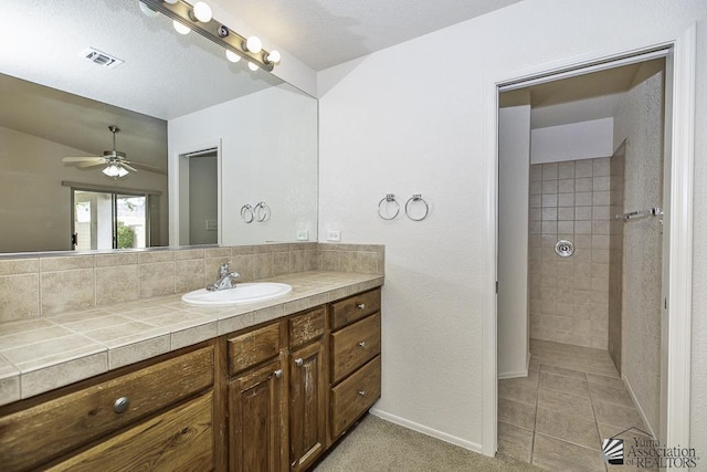 11760 E 28th Pl, Yuma, AZ 85367 - full bathroom with ceiling fan, visible vents, a tile shower, vanity, and baseboards