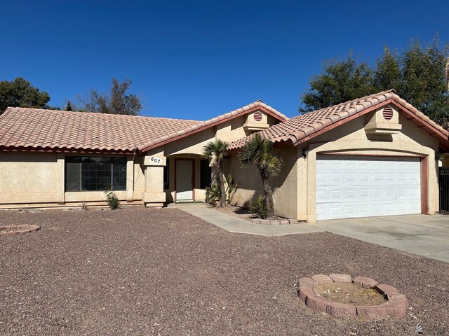 mediterranean / spanish home featuring a tiled roof, an attached garage, driveway, and stucco siding