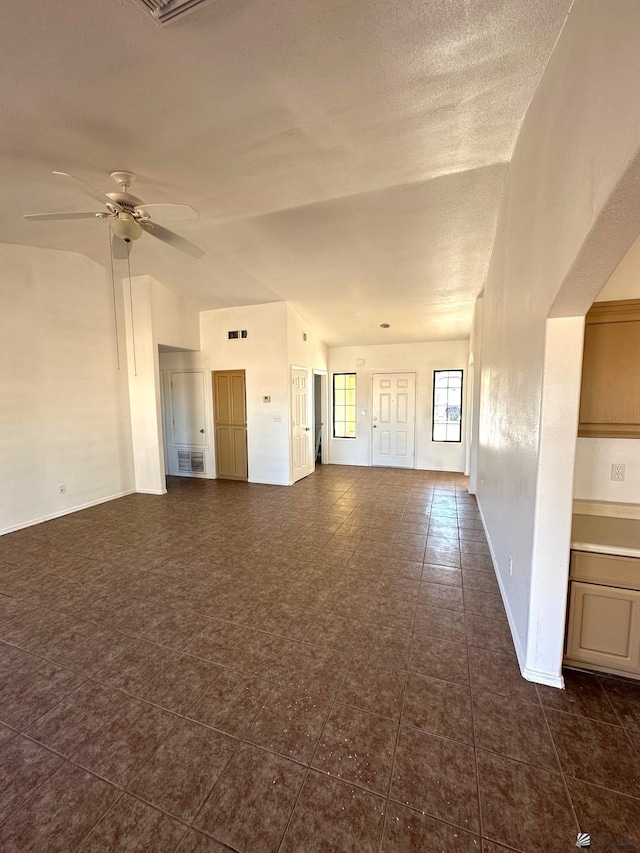empty room featuring a ceiling fan, baseboards, visible vents, and dark tile patterned floors