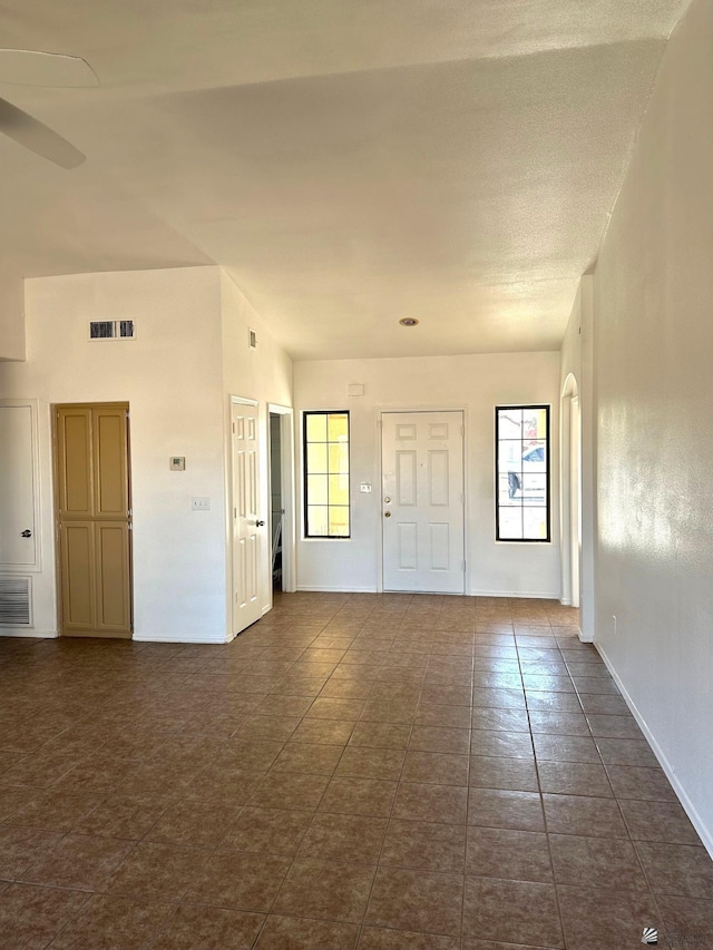spare room with visible vents, a ceiling fan, baseboards, and dark tile patterned flooring