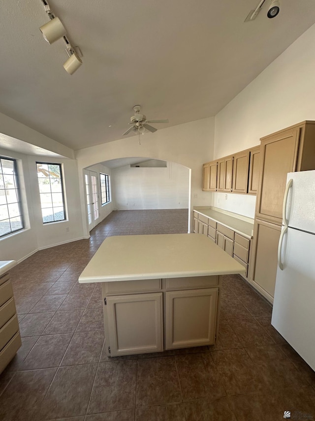 kitchen featuring ceiling fan, rail lighting, freestanding refrigerator, lofted ceiling, and dark tile patterned flooring