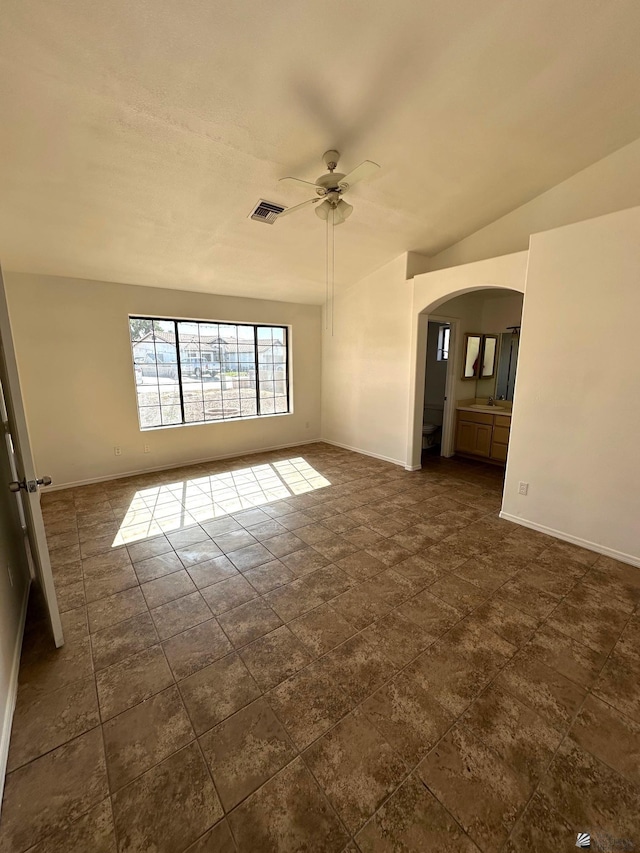 unfurnished room with visible vents, arched walkways, baseboards, and a ceiling fan