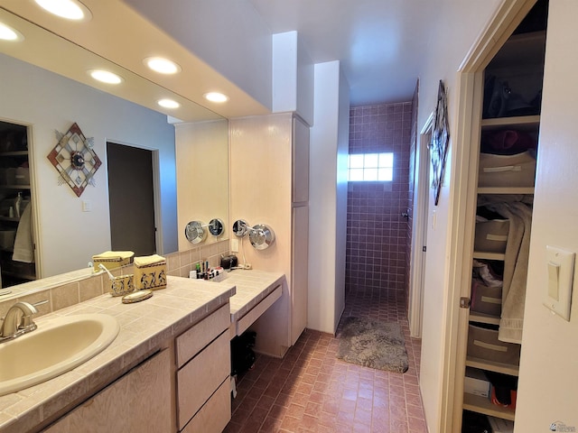 full bathroom featuring a walk in shower, brick floor, vanity, and a walk in closet