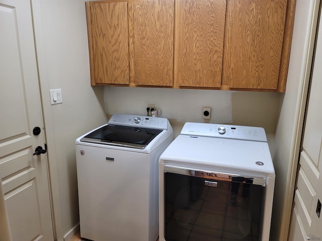 clothes washing area featuring washing machine and clothes dryer and cabinet space