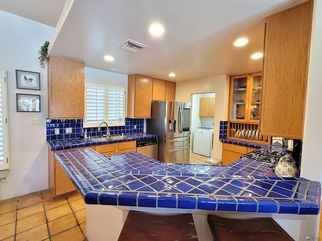 kitchen with visible vents, decorative backsplash, tile counters, a sink, and appliances with stainless steel finishes
