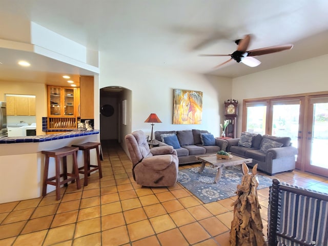 living room with light tile patterned floors, arched walkways, ceiling fan, and french doors
